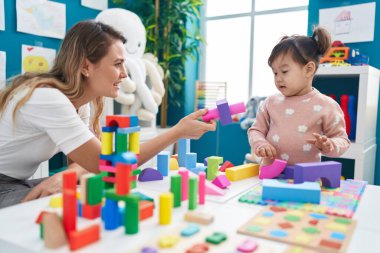 Anaokulunda inşaat bloklarıyla oynayan sevimli Çinli kız.