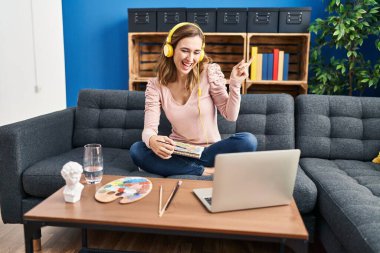 Genç, güzel bir kadın resim yapıyor. İnternetten öğretmenlere bakıyor. Gülümsüyor, mutlu bir şekilde işaret ediyor. 