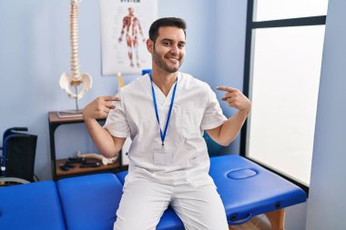 Sakallı, sakallı, acılı bir klinikte çalışan, kendine güvenen, gülümseyen, kendini gururlu ve mutlu gösteren genç bir adam.. 