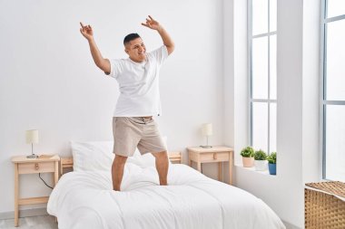 Genç Latin adam gülümsüyor. Yatak odasında dans ediyor.