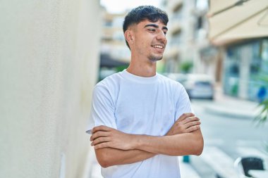 Sokakta kollarını kavuşturmuş İspanyol genç bir adam.