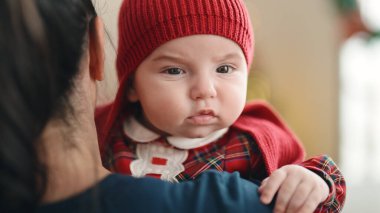 Sevimli beyaz bebek evde annesinin kollarında gevşiyor.