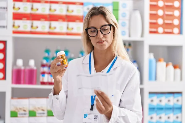 Jonge Blonde Vrouw Apotheker Holding Pillen Fles Lezen Recept Apotheek — Stockfoto