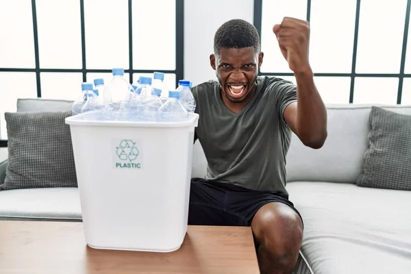 Young African American Man Holding Wastebasket Recycling Plastic Bottles Annoyed —  Fotos de Stock