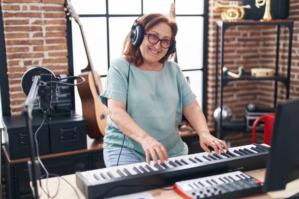 Senior woman musician playing piano keyboard at music studio