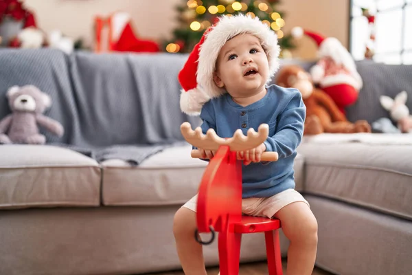 可爱的高加索婴儿在家里玩着驯鹿在圣诞树旁摇摆不定 — 图库照片