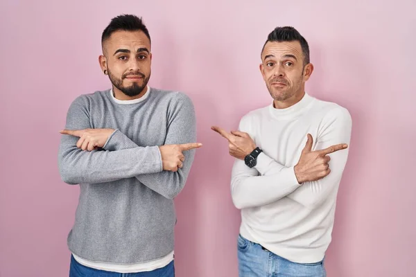 Homosexual Couple Standing Pink Background Pointing Both Sides Fingers Different — Stock Photo, Image