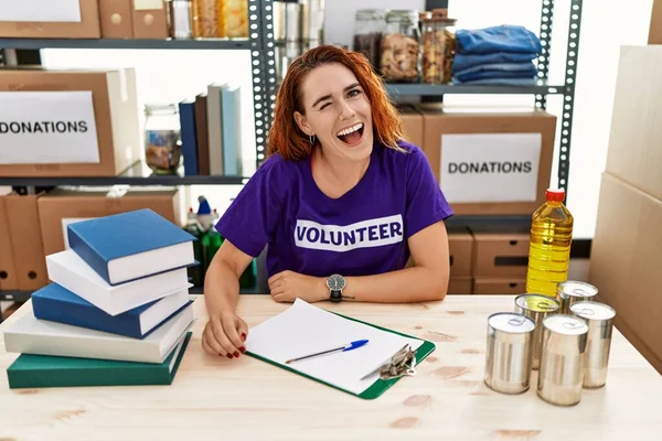 Young Redhead Woman Wearing Volunteer Shirt Donations Stand Winking Looking — Stock Photo, Image