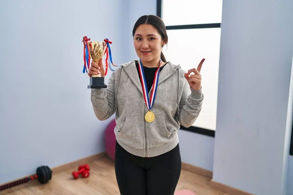 Young Latin Woman Holding Winner Trophy Smiling Happy Pointing Hand — Stockfoto