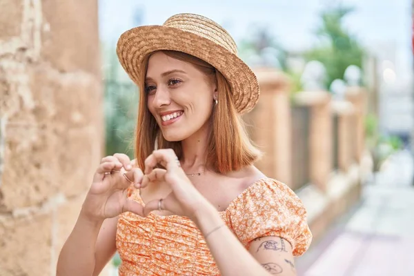 Young Redhead Woman Tourist Wearing Summer Hat Doing Heart Gesture —  Fotos de Stock