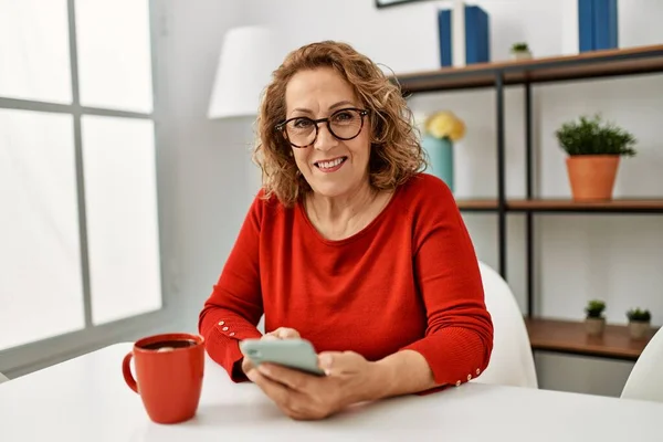 Orta Yaşlı Beyaz Kadın Akıllı Telefon Kullanıyor Evdeki Kanepede Oturup — Stok fotoğraf