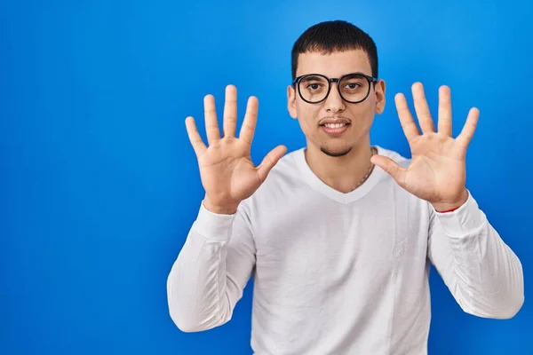 年轻的阿拉伯男子身穿随意的白色衬衫 戴着眼镜 用手指指着十号 面带微笑 自信而快乐 — 图库照片