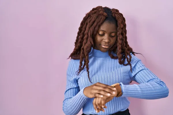 Afrikanerin Steht Vor Rosa Hintergrund Und Überprüft Die Uhrzeit Der — Stockfoto