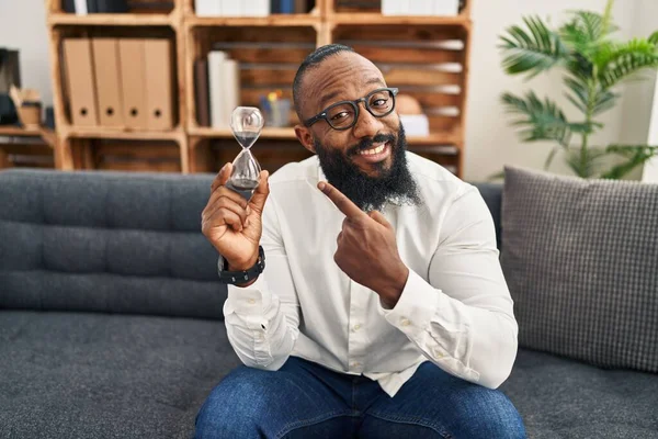 African American Man Holding Sand Clock Office Smiling Happy Pointing — Stockfoto