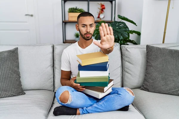 African American Young Man Holding Pile Books Sitting Sofa Doing — Stockfoto