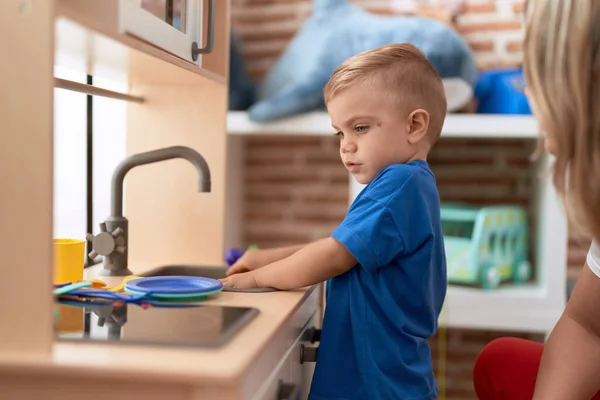 stock image Adorable toddler playing with play kitchen standing at kindergarten