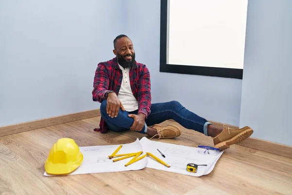 アフリカ系アメリカ人の男に座っている床に新しい家を見ながら設計図を見て カメラを見て セクシーな表情 陽気で幸せな顔 — ストック写真