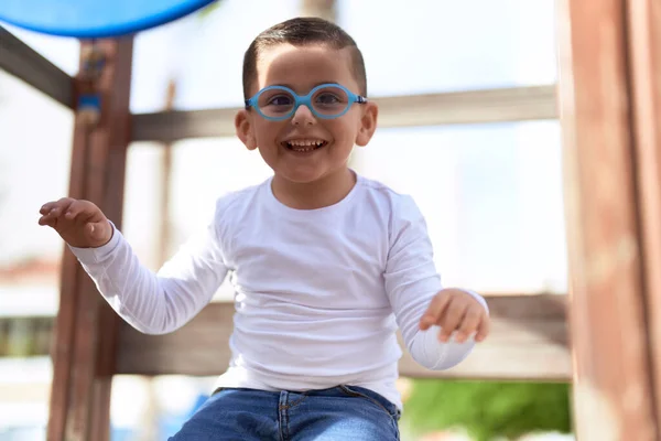 公園の遊び場でスライドで自信を持って遊んで笑っている愛らしいヒスパニック系の幼児 — ストック写真