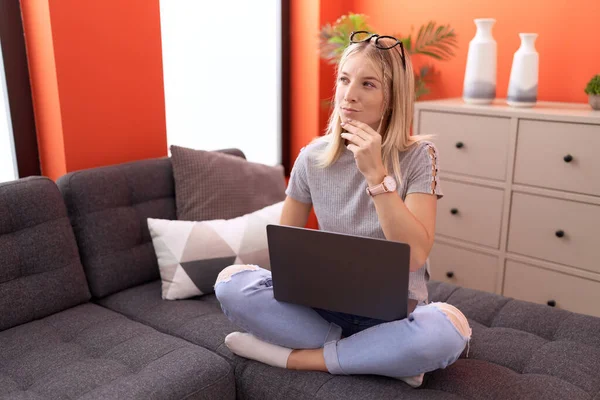 Junge Blonde Frau Benutzt Laptop Mit Zweifelhaftem Ausdruck Hause — Stockfoto