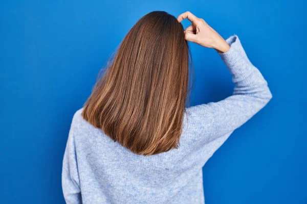 Young Woman Standing Blue Background Backwards Thinking Doubt Hand Head — Stockfoto