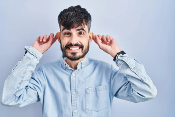 Homem Hispânico Jovem Com Barba Sobre Fundo Azul Sorrindo Puxando — Fotografia de Stock