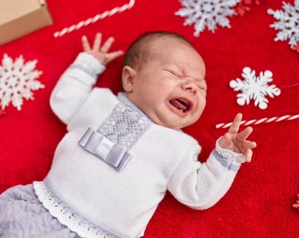 可爱的高加索婴儿躺在地板上 在孤立的红色背景下哭泣着圣诞装饰 — 图库照片