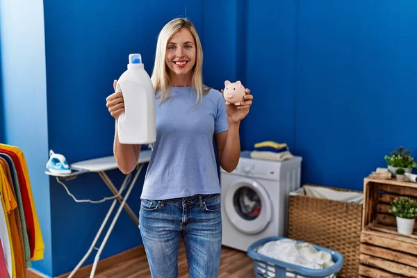 Beautiful Woman Doing Laundry Holding Detergent Bottle Piggy Bank Smiling — Zdjęcie stockowe