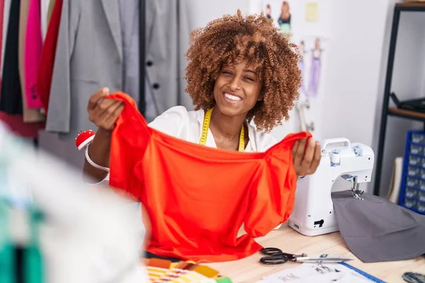 African american woman tailor smiling confident holding t shirt at atelier