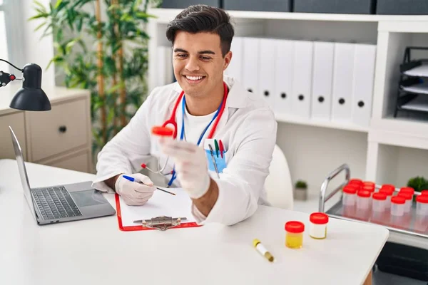 Young Hispanic Man Doctor Writing Medical Report Holding Urine Test — Foto de Stock