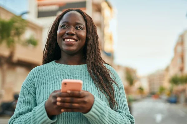 Νεαρή Αφρικανή Γυναίκα Χαμογελά Ευτυχισμένη Χρησιμοποιώντας Smartphone Στην Πόλη — Φωτογραφία Αρχείου