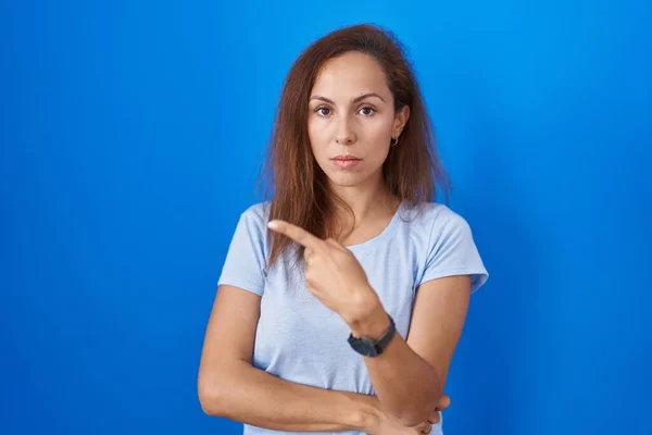 Brunette Woman Standing Blue Background Pointing Hand Finger Side Showing — Zdjęcie stockowe