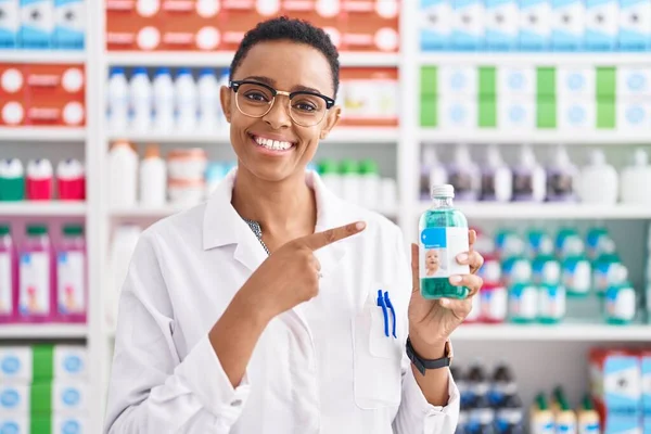 Mujer Afroamericana Trabajando Farmacia Sosteniendo Jarabe Sonriendo Feliz Señalando Con — Foto de Stock