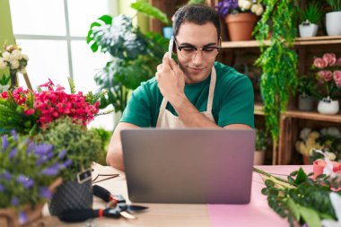 Çiçekçide dizüstü bilgisayar kullanarak konuşan İspanyol çiçekçi.