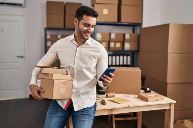 Genç İspanyol bir e-ticaret işçisi ofisteki akıllı telefon paketlerini kullanıyor.