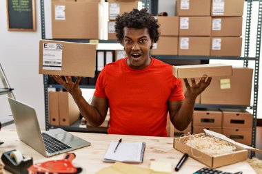 Küçük işletme şirketinde çalışan kıvırcık saçlı Afrikalı adam çılgınlığı kutluyor ve başarıya hayret ediyor gözleri açık heyecanla bağırıyor.. 