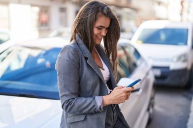 Sokakta akıllı telefon kullanan kendine güvenen genç bir kadın.