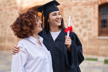 İki kadın anne ve kız, kampüs üniversitesinde birbirlerine sarılıyorlar.