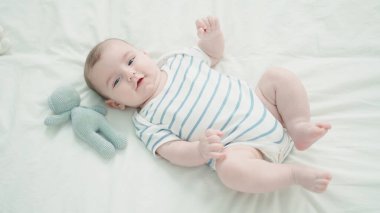Sevimli beyaz bebek yatakta kendinden emin bir şekilde gülümsüyor.