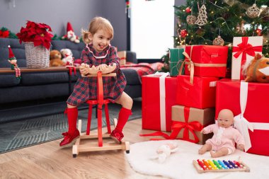 Evdeki Noel ağacında geyiklerle oynayan sevimli beyaz kız.