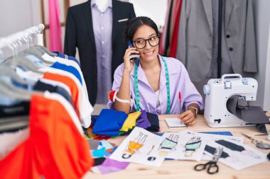 Genç, güzel İspanyol kadın terzi terzi dükkanında akıllı telefondan not defteriyle konuşuyor.