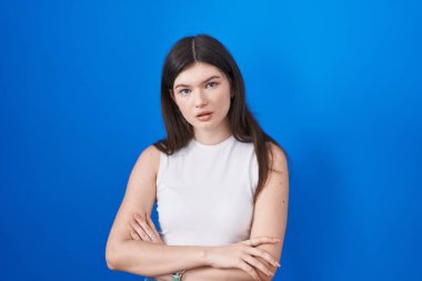 Young caucasian woman standing over blue background looking sleepy and tired, exhausted for fatigue and hangover, lazy eyes in the morning. 