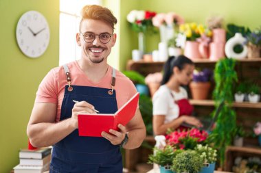 Çiçekçide dizüstü bilgisayar kullanan erkek ve kadın çiçekçiler.