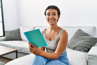 Genç İspanyol kadın evde kendinden emin bir şekilde kitap okuyordu.