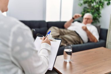 Orta yaşlı, kır saçlı bir adam psikoloji kliniğinde psikoloji seansı yapıyor.