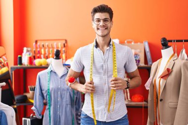 Genç İspanyol terzi atölyede kendine güvenerek gülümsüyor.