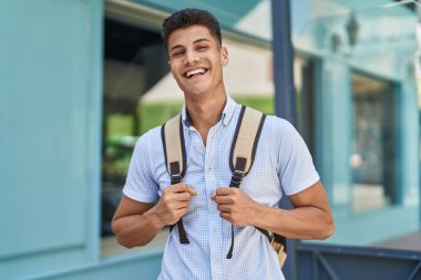 Sokakta kendinden emin gülümseyen genç İspanyol öğrenci.