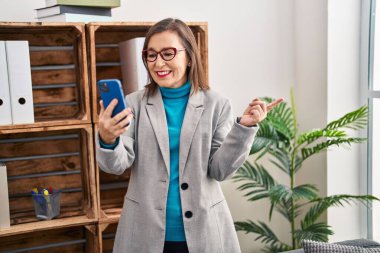 Orta yaşlı İspanyol kadın akıllı telefon kullanıyor. Video çekiyor. Gülümsüyor. 