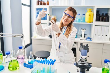 Laboratuvarda kivi enjekte eden bilim adamı üniforması giyen genç sarışın kadın.