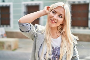 Sokakta kendine güvenen genç sarışın kadın gülümsüyor