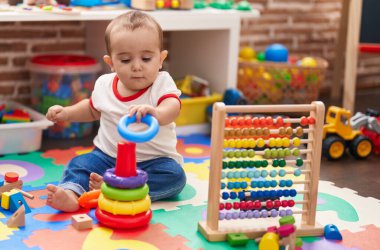 Anaokulunda yerde oturmuş abaküs ve basketbol oynayan sevimli İspanyol bebek.